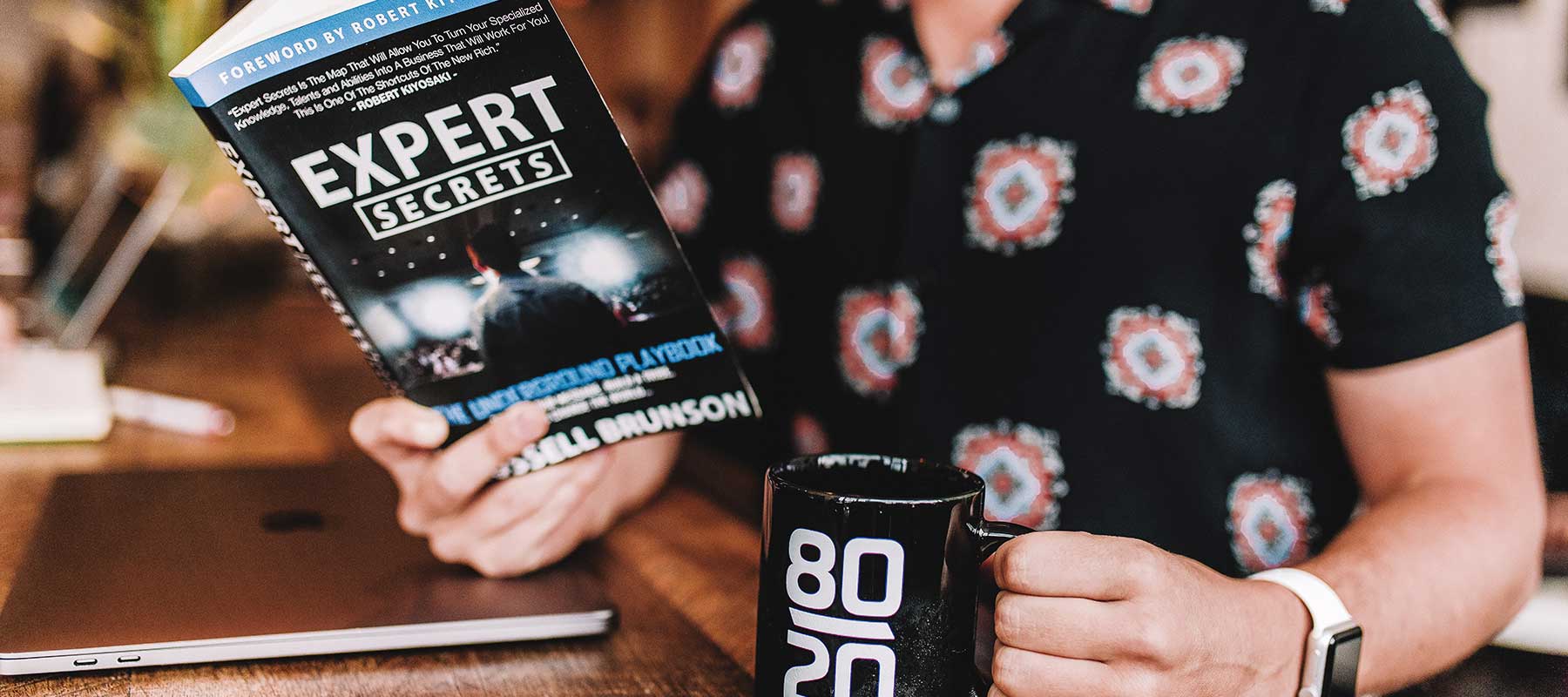 Man holding Expert Secrets book and an 80/20 mug for an affiliate page on BeyondDelights.com